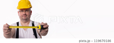 A skilled construction worker is measuring dimensions carefully using a tape measure A skilled construction worker is measuring dimensions carefully using a tape measure 119670186