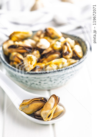 Shelled mussels meat in ceramic spoon on white table 119672071