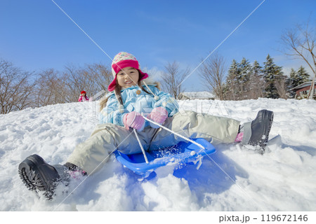 雪の公園でソリ遊びをする姉妹 119672146
