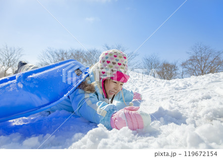 雪の公園でソリ遊びをする女の子 119672154