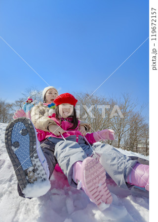 雪の公園でソリ遊びをする親子 119672157