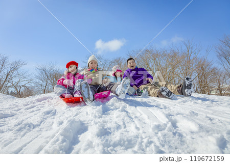 雪の公園でソリ遊びをする4人家族 119672159