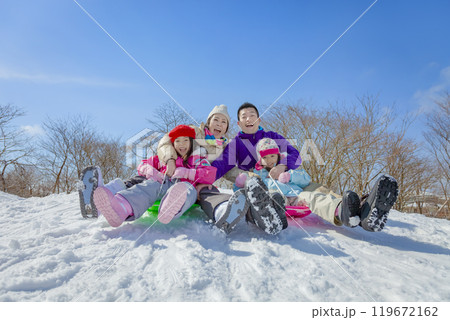 雪の公園でソリ遊びをする4人家族 119672162