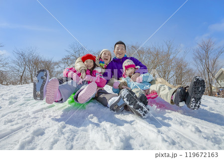 雪の公園でソリ遊びをする4人家族 119672163