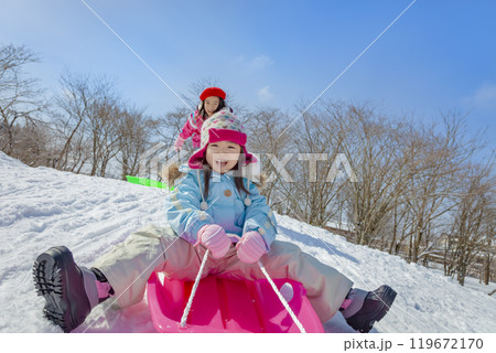 雪の公園でソリ遊びをする姉妹 119672170