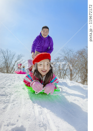 雪の公園でソリ遊びをする親子 119672172