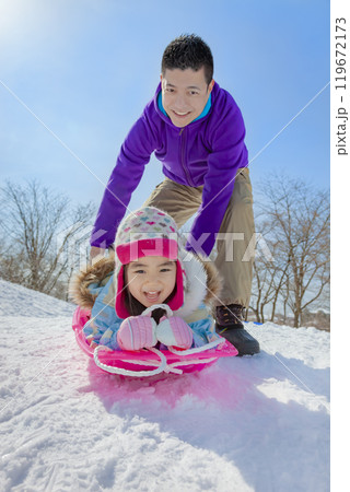 雪の公園でソリ遊びをする親子 119672173