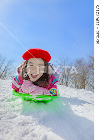 雪の公園でソリ遊びをする女の子 119672175