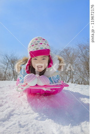 雪の公園でソリ遊びをする女の子 119672176