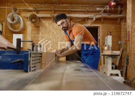 Man professional carpenter wearing workwear working with wood plank Man professional carpenter wearing workwear working with wood plank 119672747