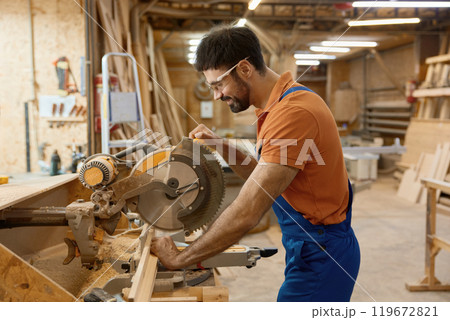Carpenter working with circular saw enjoying craftsmanship at workshop 119672821