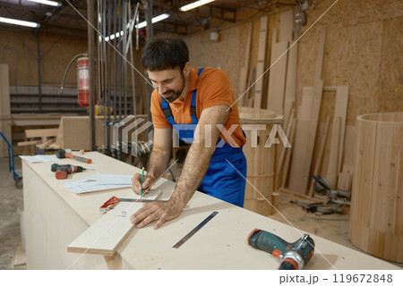 Carpenter measuring with ruler during furniture production process at workshop 119672848