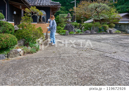 庭を掃き掃除する女性 田舎 古民家 旅館 暮らし 庭を掃き掃除する女性 田舎 古民家 旅館 暮らし 119672926