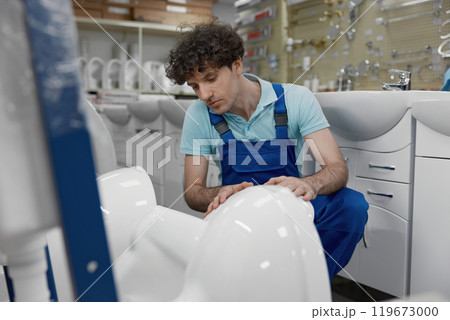 Plumber choosing new ceramic lavatory bowl at plumbing shop 119673000