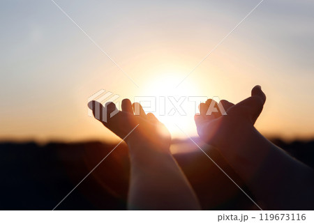 New Year's sunrise, brilliant light and rays of light shining through hands stretched out toward the rising sun, concept of hope and wishes for the future New Year's sunrise, brilliant light and rays of light shining through hands stretched out toward the rising sun, concept of hope and wishes for the future 119673116
