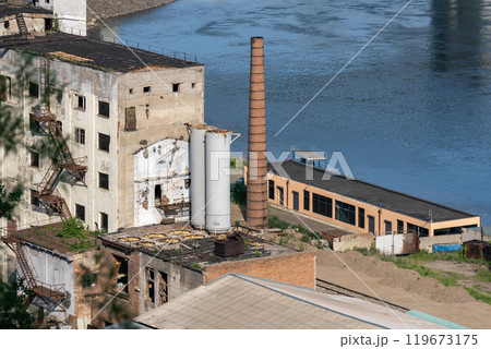 Small thermal power plant on the river bank. Brick chimney of the boiler house. 119673175