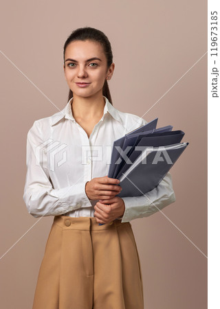 smiling businesswoman holding folders. Confident woman in white shirt looking at the camera 119673185