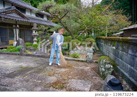 庭を掃き掃除する女性　田舎　古民家　旅館　暮らし 119673224