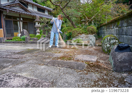 庭を掃き掃除する女性　田舎　古民家　旅館　暮らし 119673228