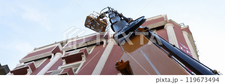 Construction cradle on crane hoist near restoring building 119673494