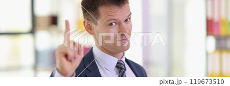 Positive businessman points up standing in company office 119673510
