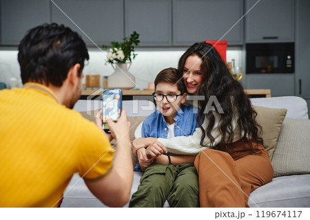 Family gathering in a cozy living room with a child and parents smiling 119674117