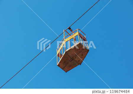 Old cable car in Dnepropetrovsk. Cable car cabins against the background of the blue sky and the urban landscape. 119674484