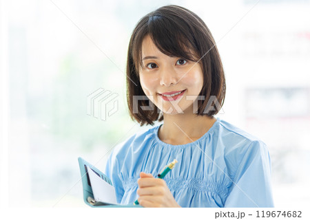 笑顔で手帳にメモをする女性01 119674682