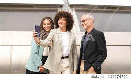 Happy businesswoman taking selfie with coworkers in city Happy businesswoman taking selfie with coworkers in city 119674762