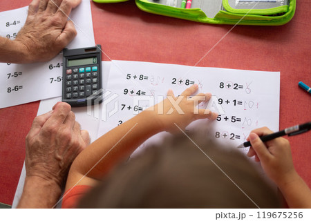 Over the shoulder view of a child who has dyslexia and dyscalculia doing math homework. 119675256