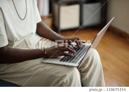 Young Man Typing on Laptop in Comfortable Setting 119675354
