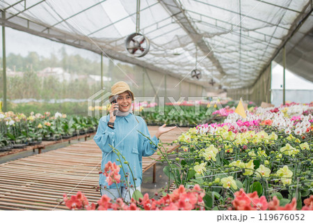 A happy gardener in a colorful greenhouse filled with beautiful orchids A happy gardener in a colorful greenhouse filled with beautiful orchids 119676052