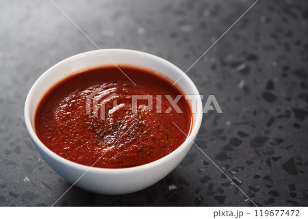 spicy tomato soup puree in white bowl on concrete background 119677472