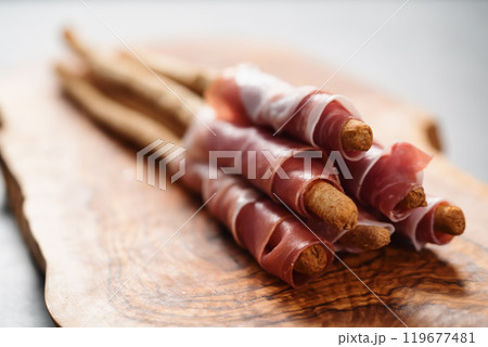 Grissini with prosciutto on olive wood board 119677481