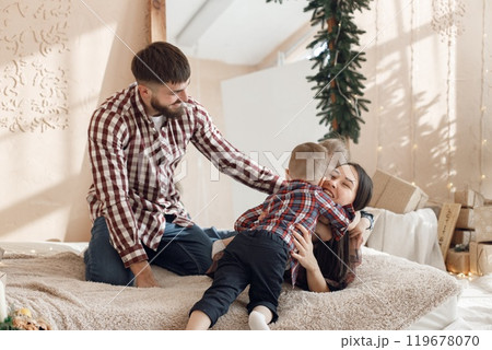 Mother, father and two their sons laying on a blanket. Boys with parents spending time together. Woman, man and two boys wearing plaid shirts. Mother, father and two their sons laying on a blanket. Boys with parents spending time together. Woman, man and two boys wearing plaid shirts. 119678070
