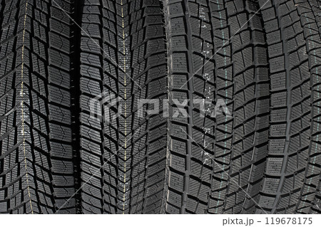 Closeup image of textured pattern of directional tread blocks and large sipes on winter non studded tires 119678175