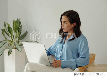 Concentrating Woman Working on Laptop in Living Room 119678306