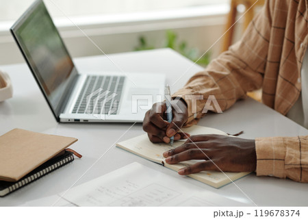 Writing Notes While Using Laptop at Desk Writing Notes While Using Laptop at Desk 119678374