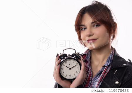 A Young Woman Dressed in a Stylish Outfit is Holding an Alarm Clock with Confidence and Charm A Young Woman Dressed in a Stylish Outfit is Holding an Alarm Clock with Confidence and Charm 119678428