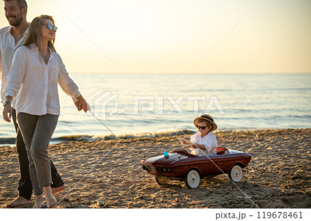 Happy young family having fun on sea shore. Mother, father and daughter on vacation. Happy young family having fun on sea shore. Mother, father and daughter on vacation. 119678461