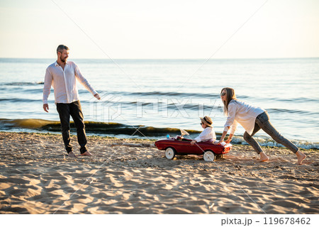 Happy young family having fun on sea shore. Mother, father and daughter on vacation. 119678462