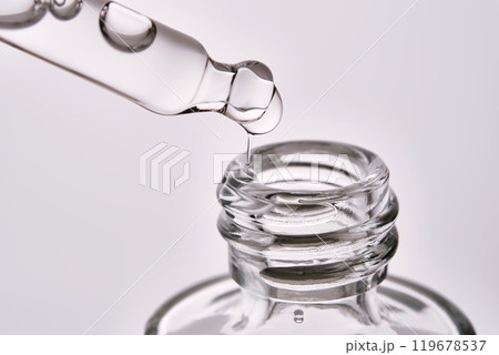 Close-up of a cosmetic bottle with a pipette showing the texture of the serum. Close-up of a cosmetic bottle with a pipette showing the texture of the serum. 119678537