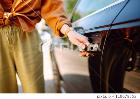 Close-up of a woman's hand opening a car door, keyless entry, outdoors. Transport, travel concept. 119678558