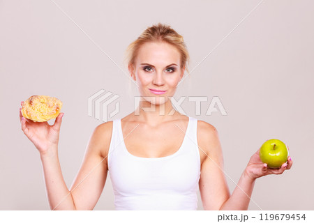 Woman holds cake and fruit in hand choosing 119679454