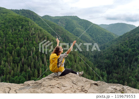 An active woman with a yellow backpack travels through the mountains. Travel concept. An active woman with a yellow backpack travels through the mountains. Travel concept. 119679553