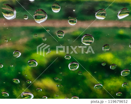 Extremely close up macro drops of water on a wet glass on natural green background. Raindrops pattern on smooth surface. Rainy day. Abstract wallpaper 119679652