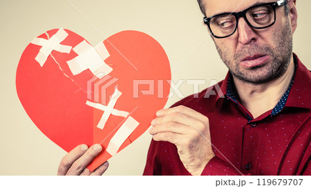 Sad adult man holding broken heart 119679707