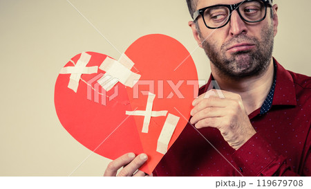 Sad adult man holding broken heart 119679708