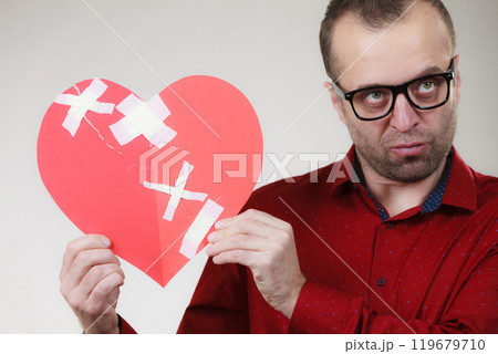 Sad adult man holding broken heart 119679710