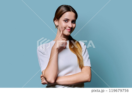 Portrait of beautiful young girl with long red hair looking at camera on blue background 119679756